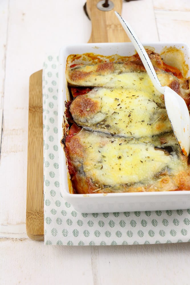 Zoete aardappel lasagne met spinazie, aubergine, en paprika, vers uit de oven, geserveerd in een ovenschaal met een knapperige korstje van mozzarella en kleurrijke lagen van verse groenten.