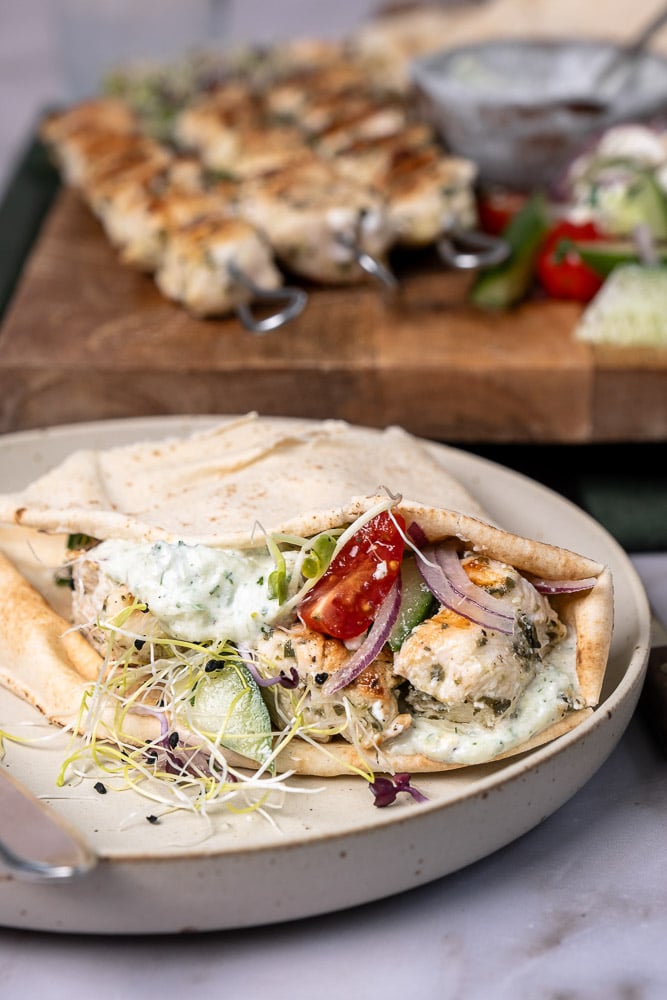 Een heerlijk recept voor gegrilde souvlaki spiesen van kip, geserveerd met pita, frisse Griekse salade, en een schaaltje zelfgemaakte tzatziki, perfect voor een zomerse maaltijd in de Mediterrane stijl.