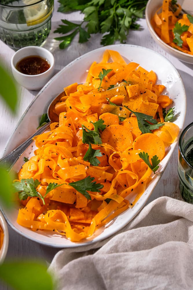 Frisse wortel salade met een Oosterse dressing van sesamolie, rijstazijn, maple syrup en sojasaus, gegarneerd met koriander en sesamzaadjes. Een gezonde, knapperige salade die perfect past bij een BBQ of als lichte lunch. Tiktok viral recept