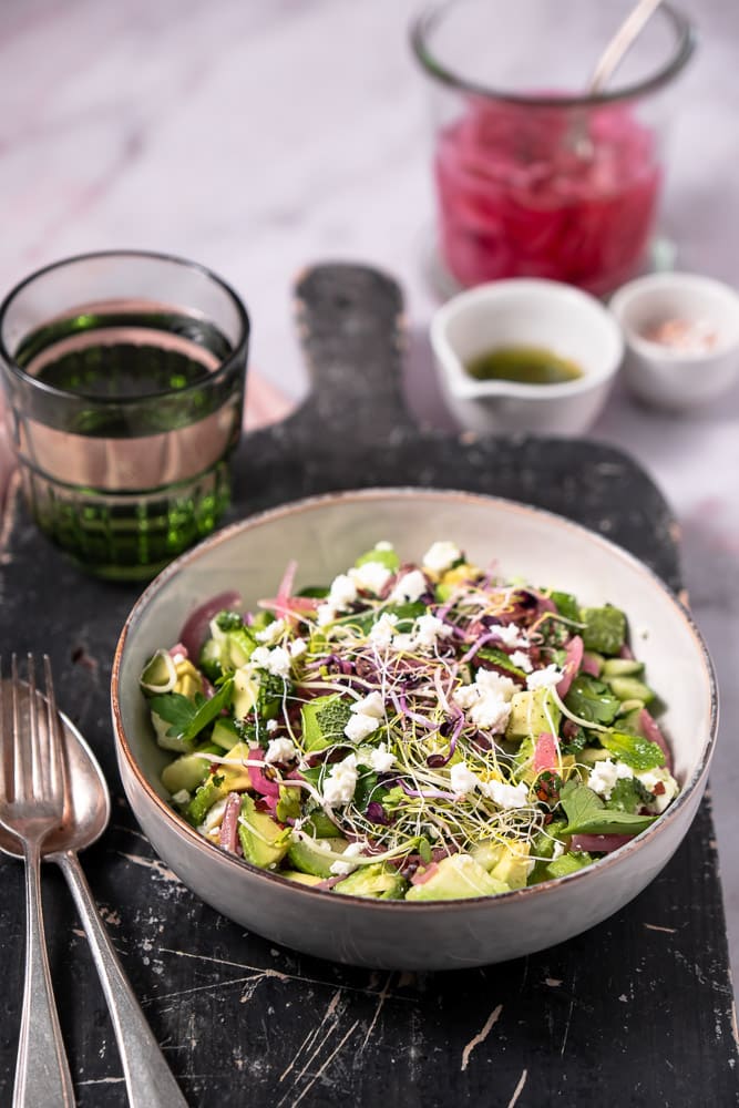 Makkeiljk recept voor gezonde avocado salade met komkommer, feta, verse munt en zoetzure rode ui, geserveerd met een frisse citroendressing, perfect als bijgerecht of lichte lunch.