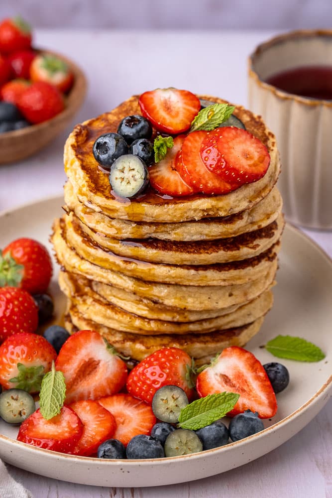 Recept voor gezonde cottage cheese pannenkoeken, gemaakt van havermout, eieren en cottage cheese, geserveerd met vers fruit als topping voor een eiwitrijk ontbijt of lunch.