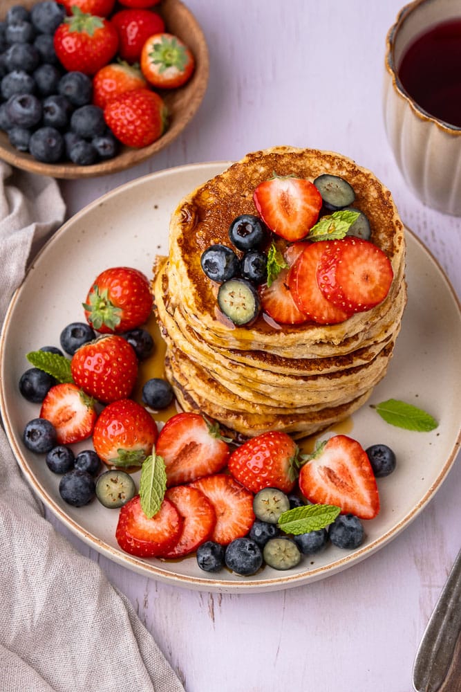 Recept voor gezonde cottage cheese pannenkoeken, gemaakt van havermout, eieren en cottage cheese, geserveerd met vers fruit als topping voor een eiwitrijk ontbijt of lunch.