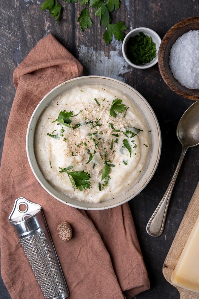 Recept voor romige en koolhydraatarme bloemkoolpuree – een gezond alternatief voor aardappelpuree, boordevol smaak dankzij Parmezaanse kaas en kruiden. Perfect als bijgerecht voor elke maaltijd!