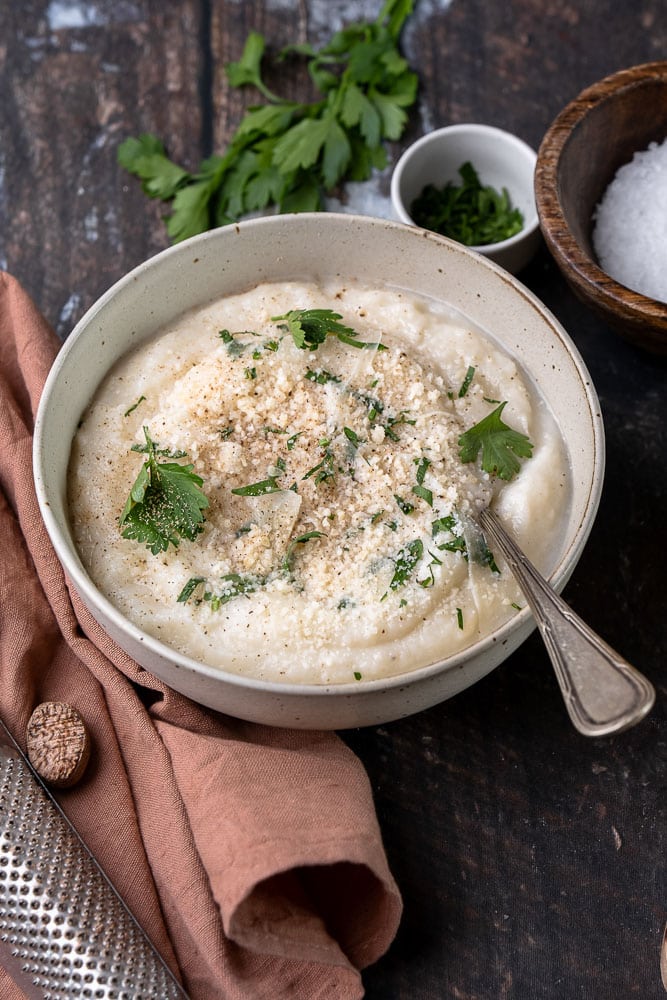 Recept voor romige en koolhydraatarme bloemkoolpuree – een gezond alternatief voor aardappelpuree, boordevol smaak dankzij Parmezaanse kaas en kruiden. Perfect als bijgerecht voor elke maaltijd!