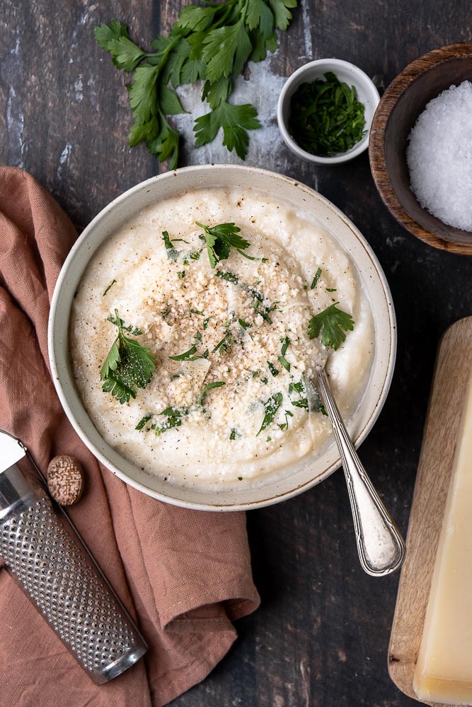 Recept voor romige en koolhydraatarme bloemkoolpuree – een gezond alternatief voor aardappelpuree, boordevol smaak dankzij Parmezaanse kaas en kruiden. Perfect als bijgerecht voor elke maaltijd!