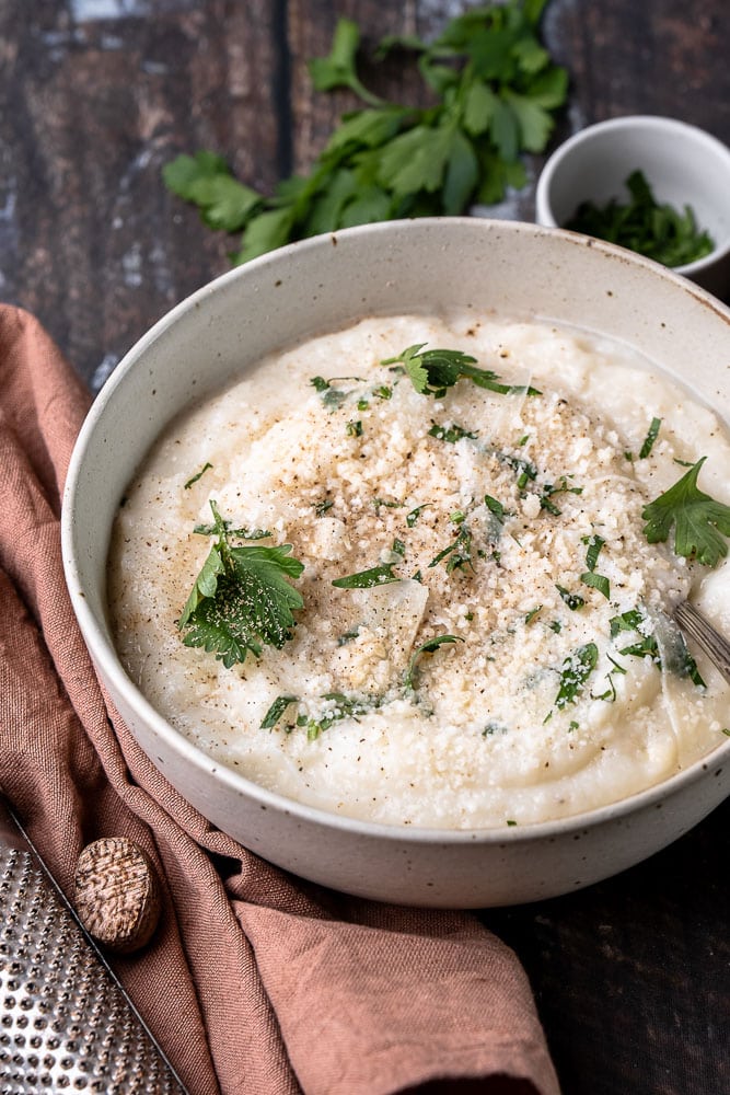 Recept voor romige en koolhydraatarme bloemkoolpuree – een gezond alternatief voor aardappelpuree, boordevol smaak dankzij Parmezaanse kaas en kruiden. Perfect als bijgerecht voor elke maaltijd!