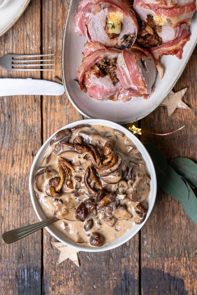 Koolhydraatarme champignon roomsaus geserveerd bij gevulde varkenshaas met brie en champignons, een romig en smaakvol gerecht voor een feestelijk diner. Deze champignonsaus is ook heerlijk bij andere vleesgerechten zoals biefstuk, of juist heerlijk met een bord pasta.