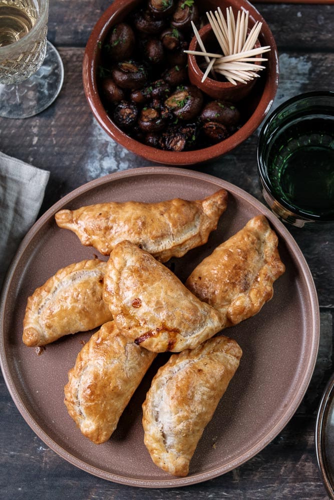 Empanadas met tonijn, paprika, rode ui en gerookt paprikapoeder, geserveerd als knapperig Spaans tapasgerecht. Empanada de atun, spaans tapas hapje met tonijn