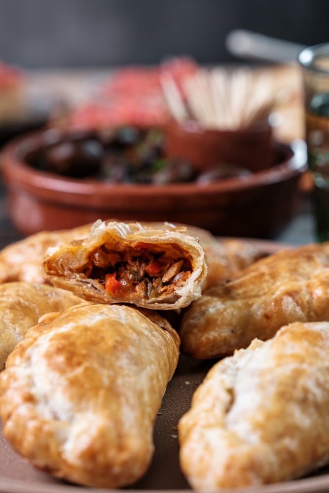 Empanadas met tonijn, paprika, rode ui en gerookt paprikapoeder, geserveerd als knapperig Spaans tapasgerecht. Empanada de atun, spaans tapas hapje met tonijn