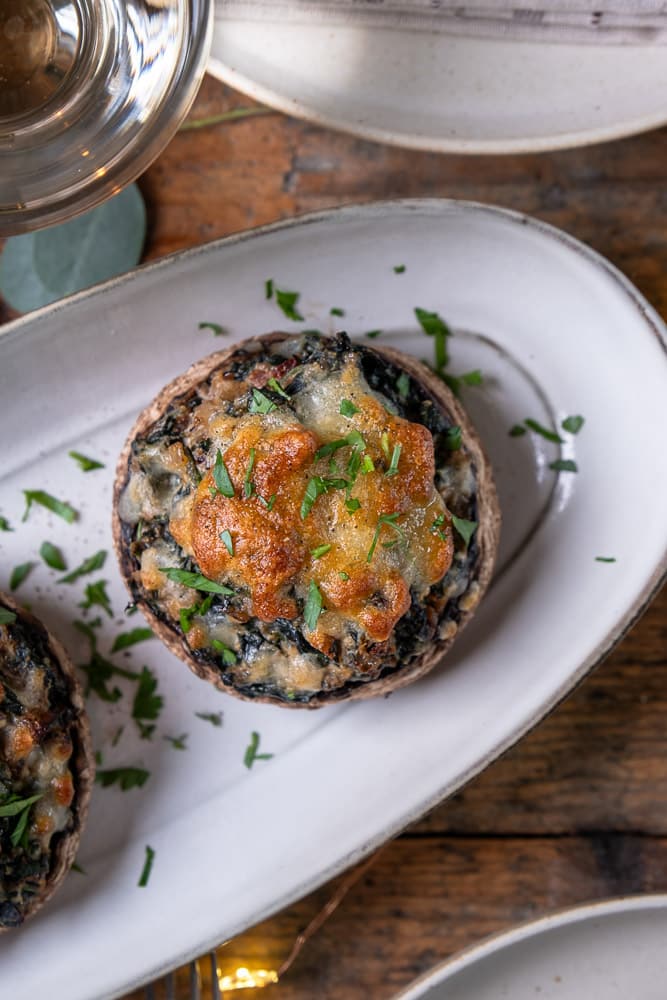 Gevulde portobello met spinazie, ricotta, zongedroogde tomaten, walnoten en mozzarella, perfect als vegetarisch voorgerecht of feestelijk gerecht voor Kerst. Recept voor gevulde portobello uit de oven.