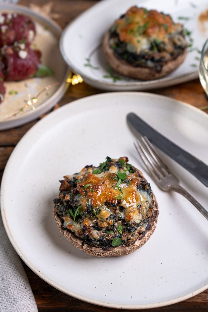 Gevulde portobello met spinazie, ricotta, zongedroogde tomaten, walnoten en mozzarella, perfect als vegetarisch voorgerecht of feestelijk gerecht voor Kerst. Recept voor gevulde portobello uit de oven.