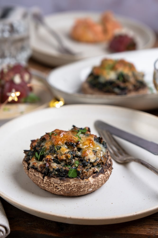 Gevulde portobello met spinazie, ricotta, zongedroogde tomaten, walnoten en mozzarella, perfect als vegetarisch voorgerecht of feestelijk gerecht voor Kerst. Recept voor gevulde portobello uit de oven.