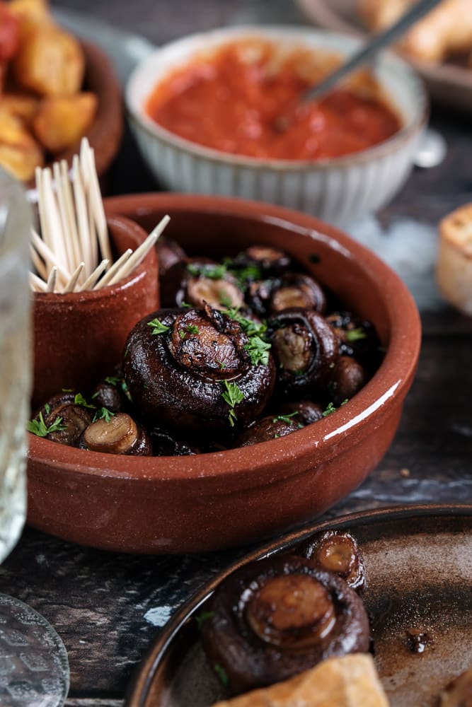 Knoflook champignons, gebakken in knoflookolie met verse peterselie en gerookt paprikapoeder, geserveerd als tapasgerecht. Tapas hapje met champignons, Champiñones al ajillo