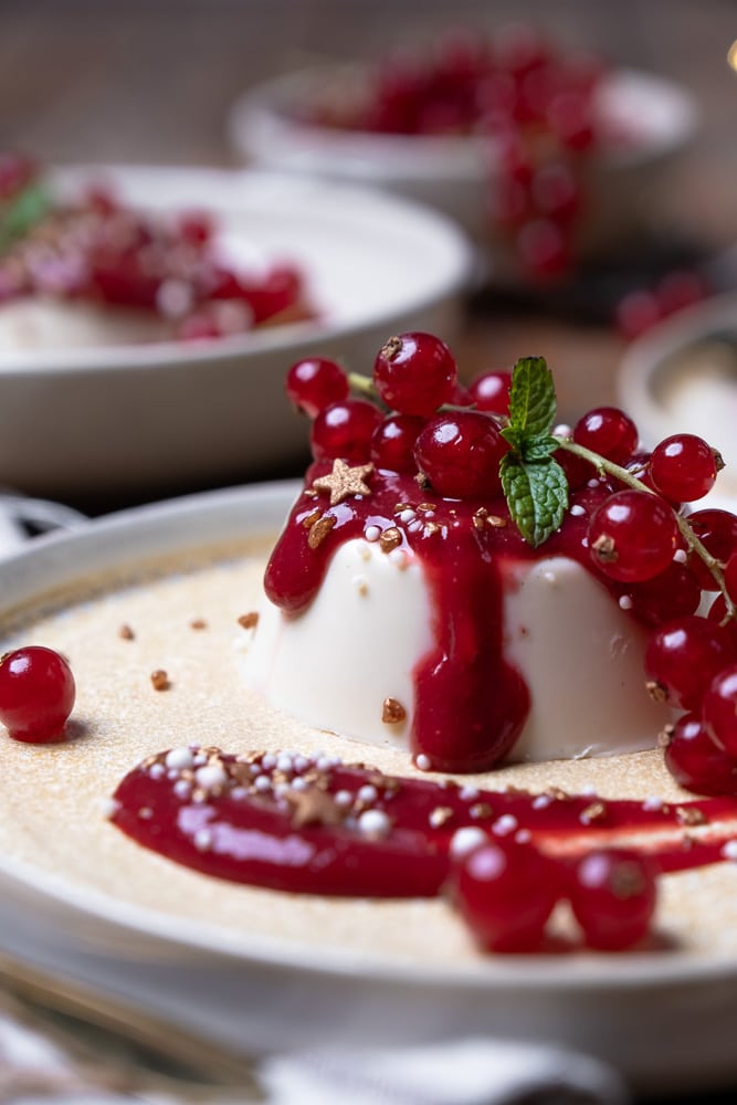 Romige panna cotta met rood fruit en frambozensaus, een feestelijk Italiaans nagerecht. Zelf panna cotta maken is eenvoudig met dit klassieke panna cotta recept, ideaal voor een diner of kerstdessert.