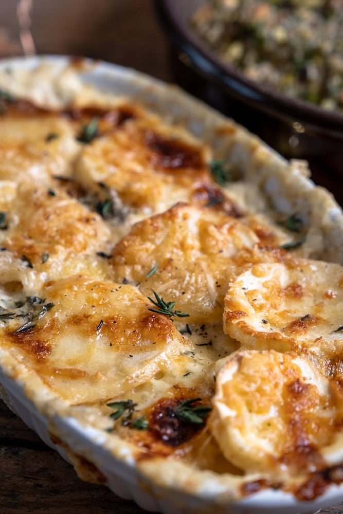 Makkelijk recept voor romige pastinaak gratin met Parmezaanse kaas en oude kaas, gegarneerd met verse tijm, een feestelijk bijgerecht uit de oven.