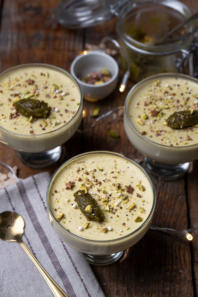 Romige pistache panna cotta, recept voor panna cotta met pistache pasta, geserveerd met een topping van fijngehakte pistachenoten, een elegant Italiaans dessert perfect voor elke gelegenheid. Feestelijk nagerecht. 