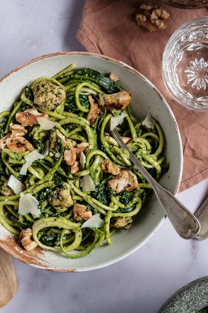 Courgette spaghetti met kip en zelfgemaakte groene pesto van spinazie en walnoten. Dit koolhydraatarme gerecht is een gezonde en smaakvolle variant op traditionele pasta pesto, boordevol groenten en eiwitten. De courgette spaghetti is eenvoudig te maken met een spiraalsnijder en wordt gecombineerd met malse kipfilet, Italiaanse kruiden en een romige pesto zonder pakjes of zakjes. Een perfect gerecht voor wie een voedzame en lichte maaltijd zoekt!