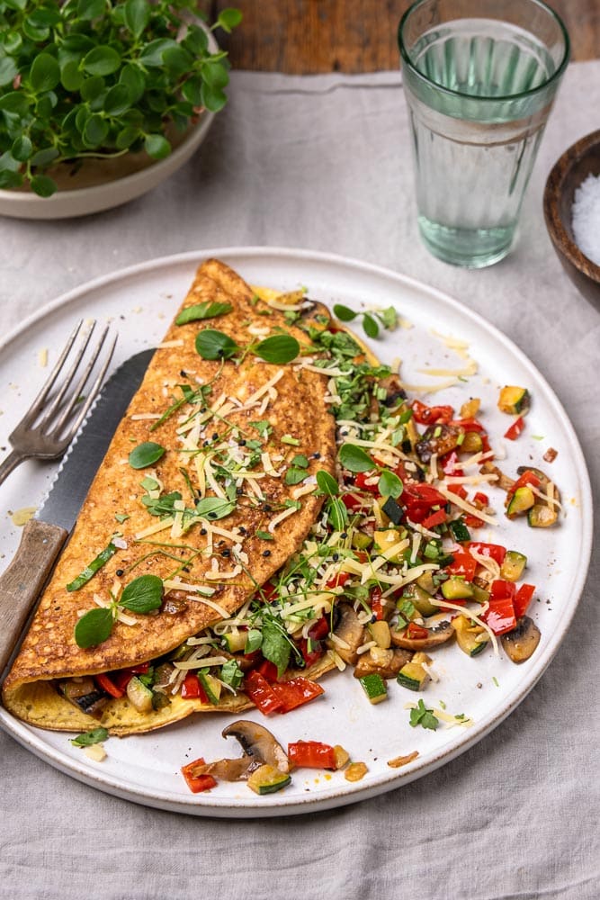 Omelet met groenten, groenten omelet gevuld met paprika, champignons en spinazie. Een voedzaam en eiwitrijk gerecht dat perfect is als lunch, ontbijt of snelle avondmaaltijd. Ook bekend als boerenomelet en ideaal om mee te nemen als makkelijk lunchgerecht op werk. Groenteomelet, groenten omelet, omelet groenten.