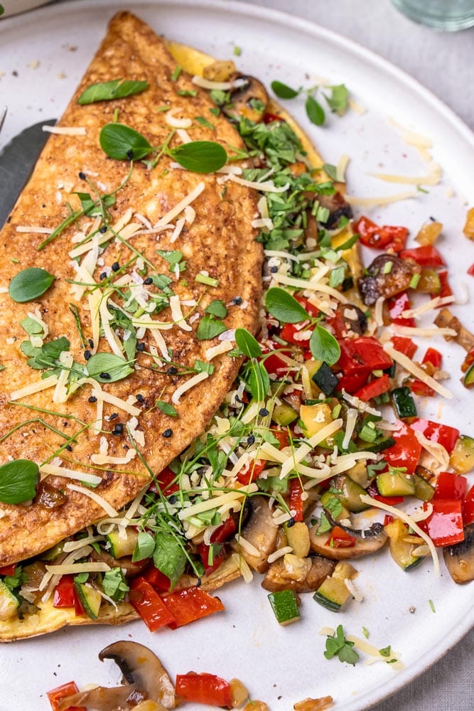 Omelet met groenten, groenten omelet gevuld met paprika, champignons en spinazie. Een voedzaam en eiwitrijk gerecht dat perfect is als lunch, ontbijt of snelle avondmaaltijd. Ook bekend als boerenomelet en ideaal om mee te nemen als makkelijk lunchgerecht op werk. Groenteomelet, groenten omelet, omelet groenten.